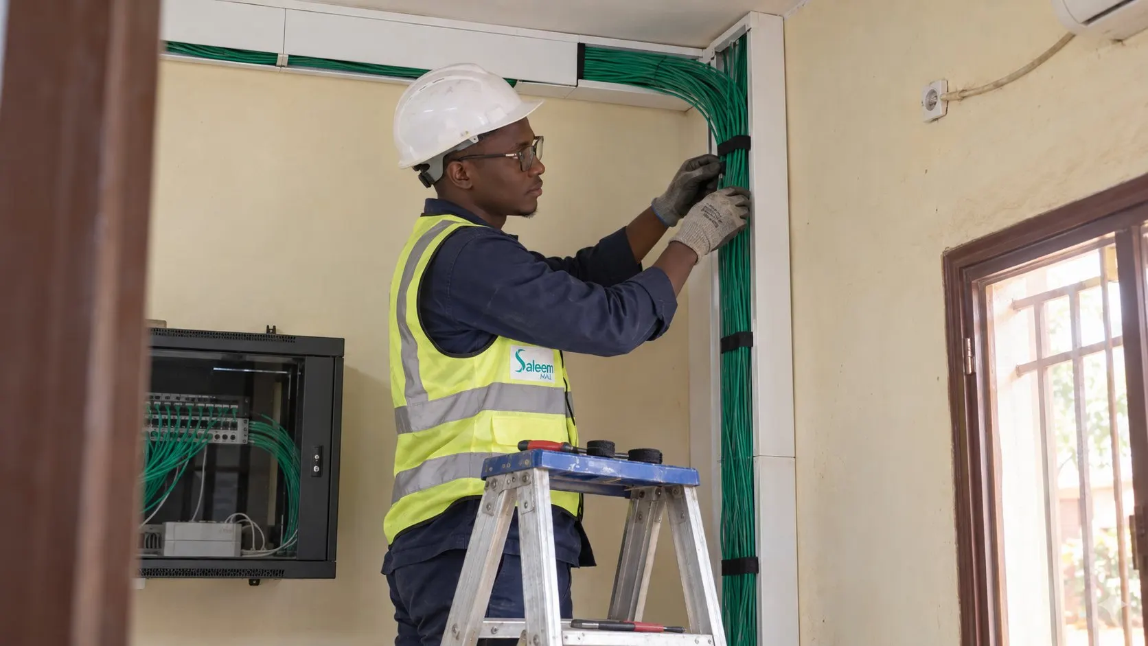 Technicien informatique organisant des câbles dans une goulotte à Bamako